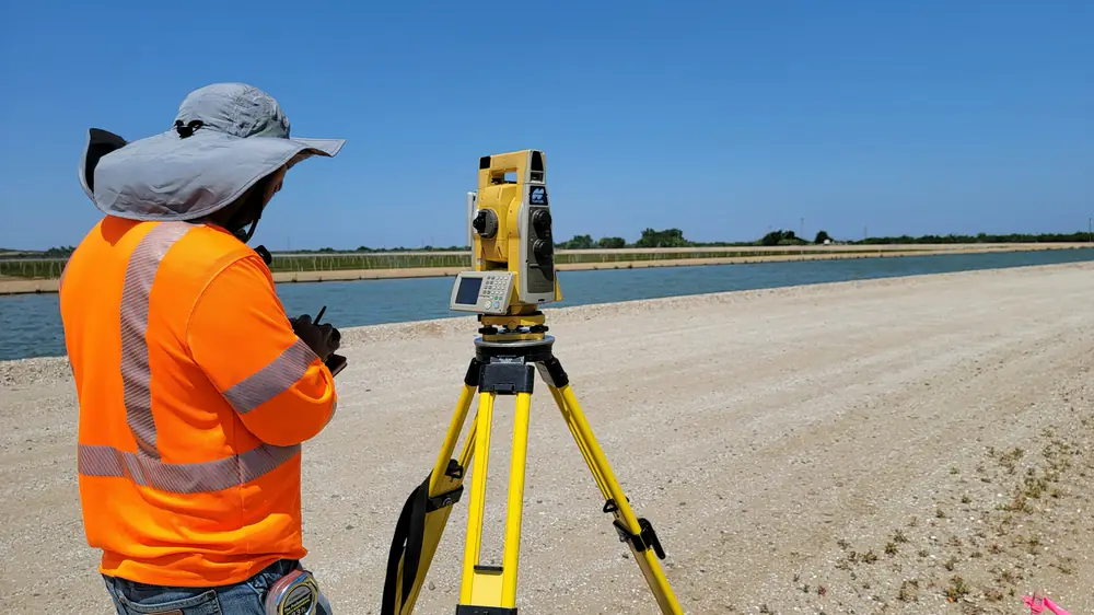 Surveyor seen from behind at a total station on a construction site
